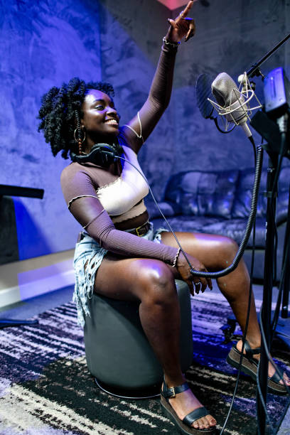 Independent vocalist seated beside a studio microphone