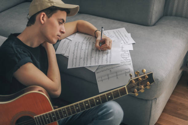 Songwriter working through sheet music with an acoustic guitar